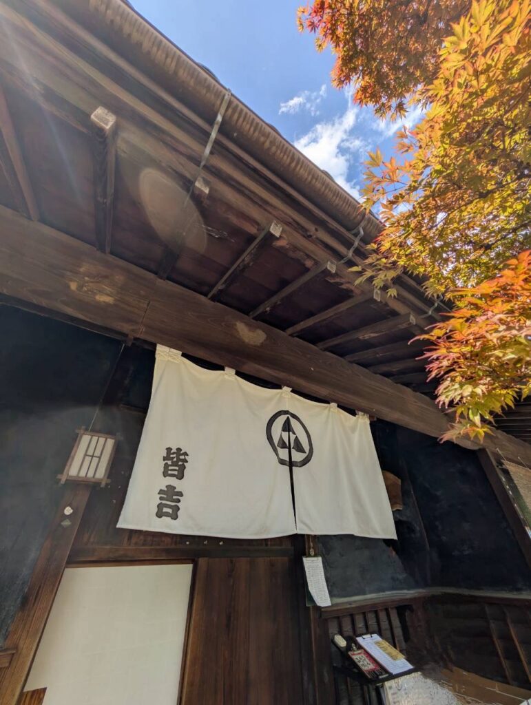ほうとうの人気店・皆吉の外観。古民家の軒下に「皆吉」と染め抜かれた白い暖簾