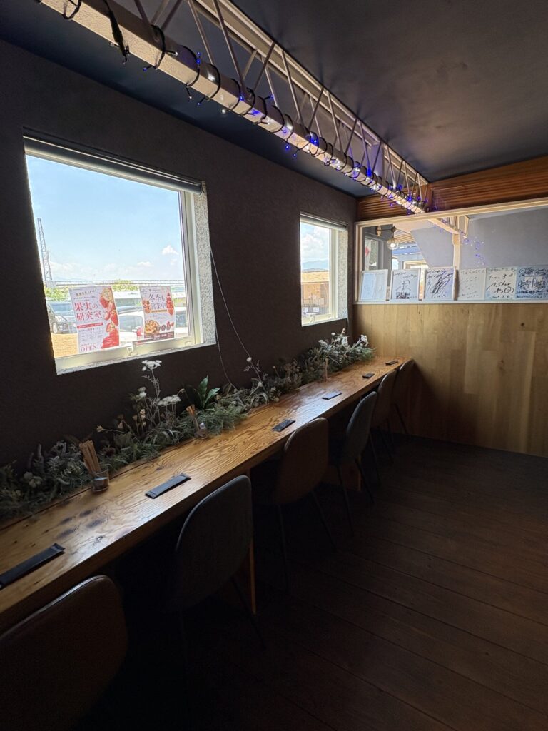 志村葡萄研究所のカフェ店内。窓際に並ぶ木のカウンター席とドライフラワーの装飾