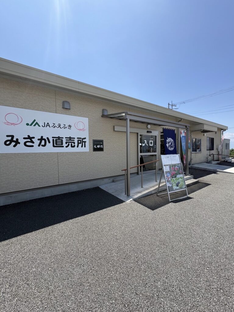 山梨・笛吹市のJAふえふき みさか直売所の外観。青空の下、白い看板に「みさか直売所」の文字