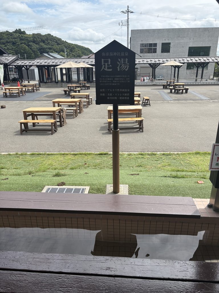 おもてなし広場の足湯。弥彦湯神社温泉の案内板が立つ