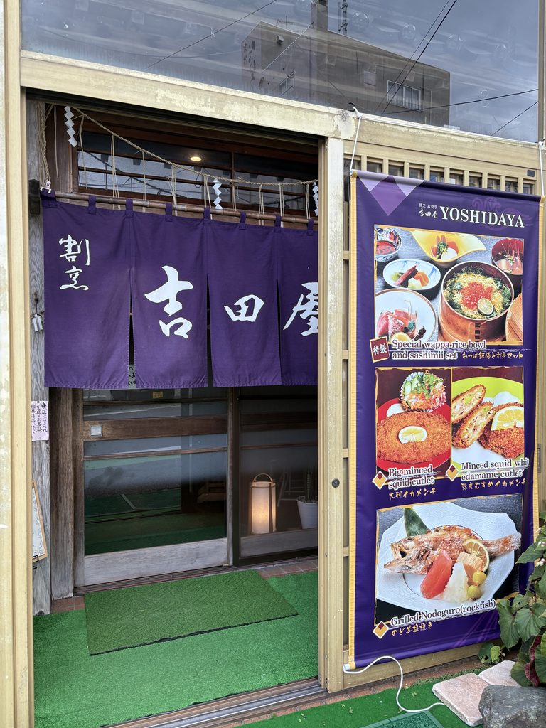 割烹お食事 吉田屋の店構え。紫の暖簾とメニューの幕